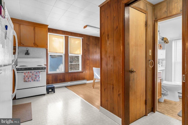 kitchen featuring a baseboard heating unit, wooden walls, and white appliances