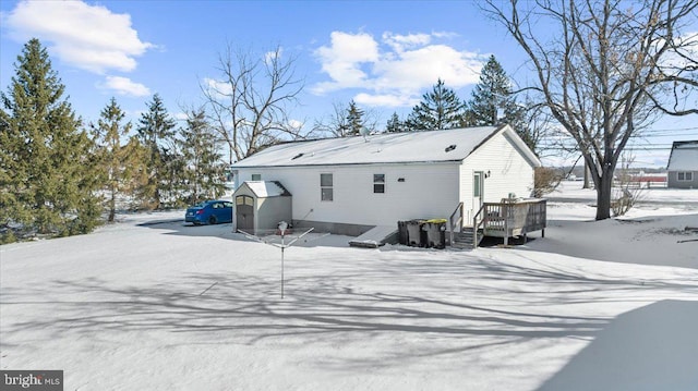 snow covered back of property with a wooden deck