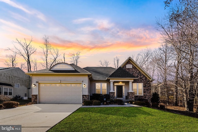 view of front of property with a yard, a shingled roof, a garage, stone siding, and driveway