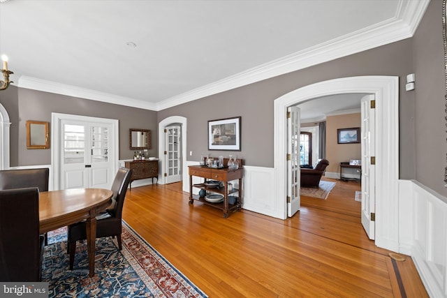 dining space with wood-type flooring, ornamental molding, and french doors