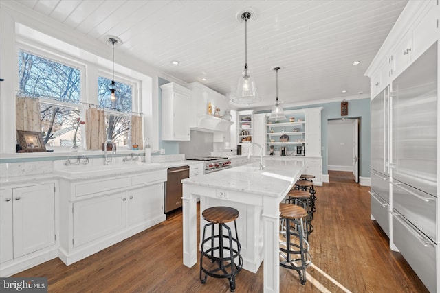 kitchen with sink, hanging light fixtures, appliances with stainless steel finishes, an island with sink, and white cabinets