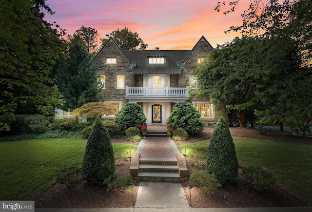 view of front of house with a balcony and a yard