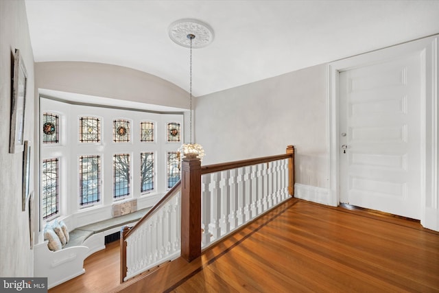 corridor with brick ceiling, a chandelier, vaulted ceiling, and hardwood / wood-style floors