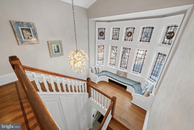 stairs featuring hardwood / wood-style flooring, a high ceiling, a healthy amount of sunlight, and a chandelier