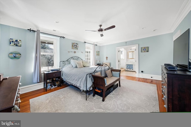 bedroom featuring connected bathroom, crown molding, wood-type flooring, and ceiling fan