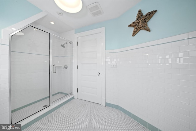 bathroom with a shower with door and tile patterned flooring