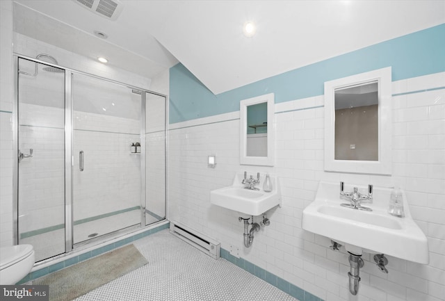 bathroom featuring tile patterned floors, toilet, tile walls, a shower with door, and a baseboard heating unit