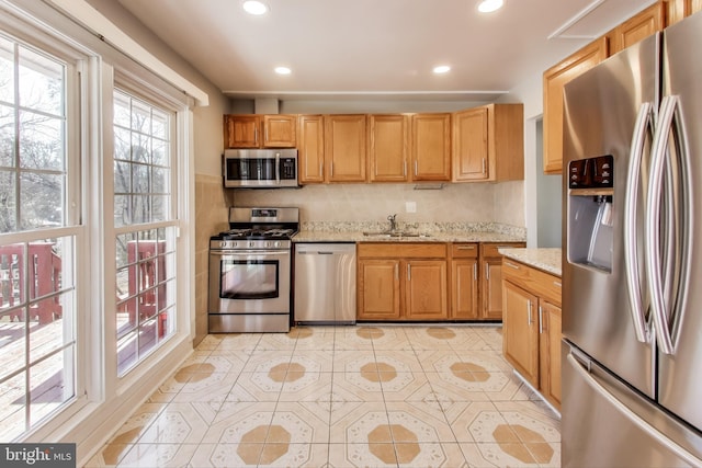 kitchen featuring light tile patterned flooring, sink, decorative backsplash, stainless steel appliances, and light stone countertops