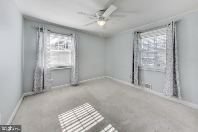 spare room featuring ceiling fan, light colored carpet, and a healthy amount of sunlight