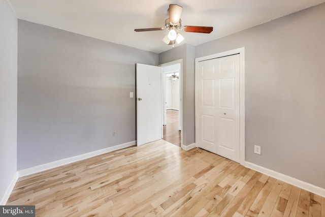 unfurnished bedroom with ceiling fan, a closet, and light wood-type flooring