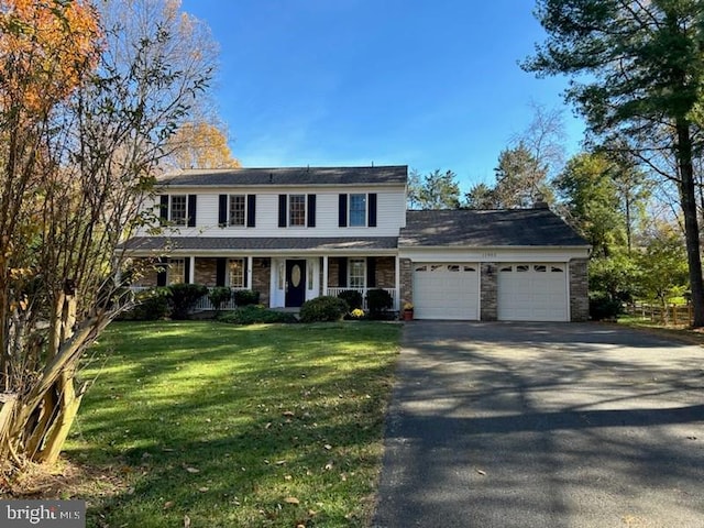 view of front of property featuring a garage, a front lawn, and covered porch