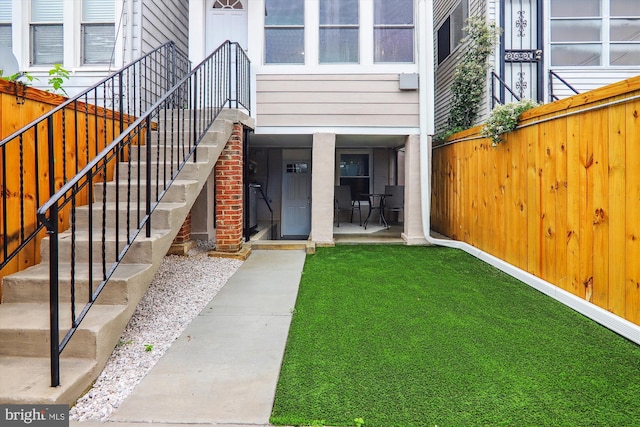 view of exterior entry with a patio area and a lawn