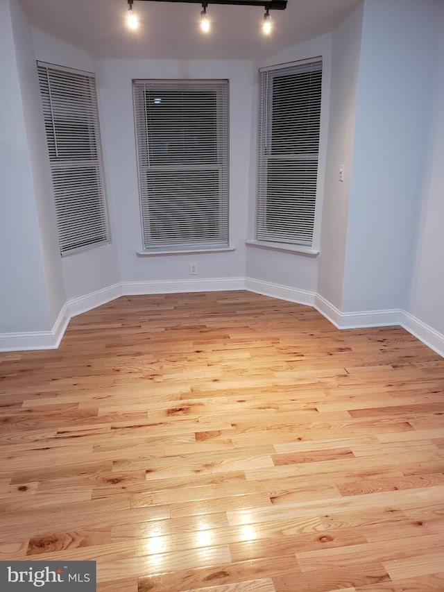 empty room featuring light hardwood / wood-style flooring and track lighting