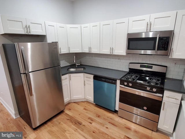 kitchen with sink, stainless steel appliances, white cabinetry, and light hardwood / wood-style floors