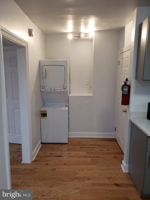 laundry area with stacked washer / dryer and hardwood / wood-style floors