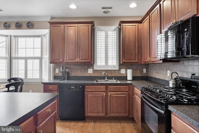 kitchen with sink, light wood-type flooring, black appliances, ornamental molding, and decorative backsplash