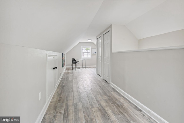 corridor featuring vaulted ceiling and light hardwood / wood-style flooring