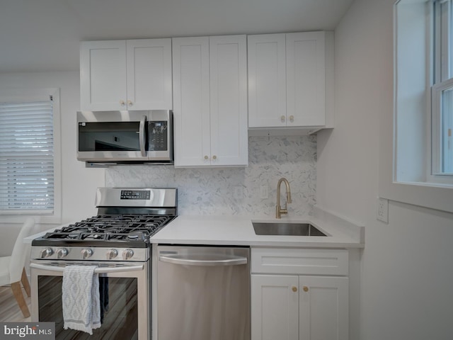 kitchen featuring backsplash, appliances with stainless steel finishes, sink, and white cabinets