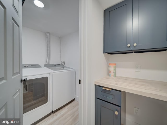 washroom with cabinets, light hardwood / wood-style floors, and washing machine and clothes dryer