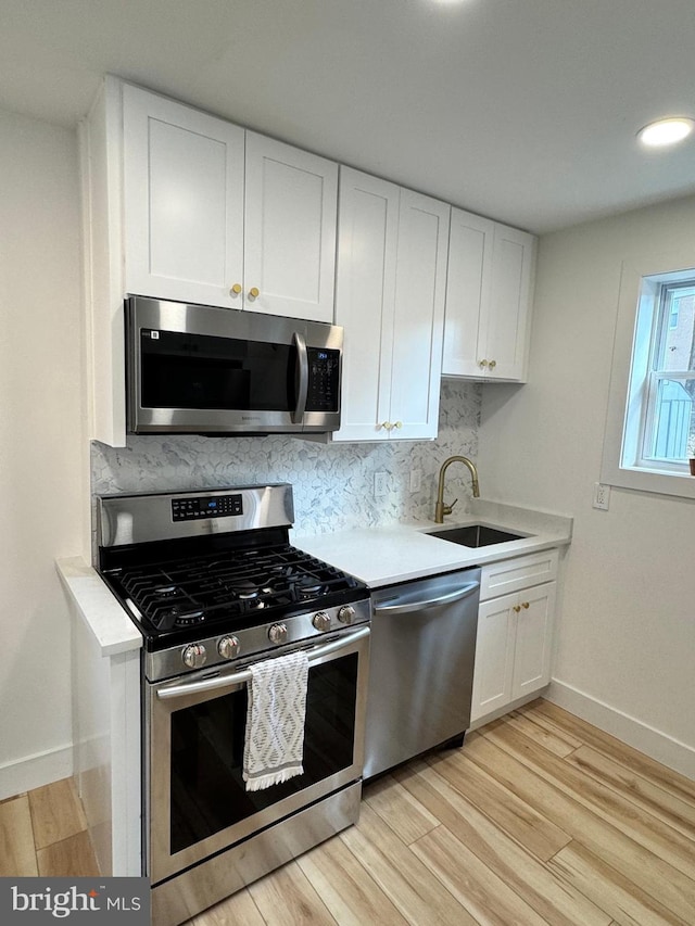 kitchen featuring sink, white cabinetry, tasteful backsplash, light hardwood / wood-style flooring, and stainless steel appliances