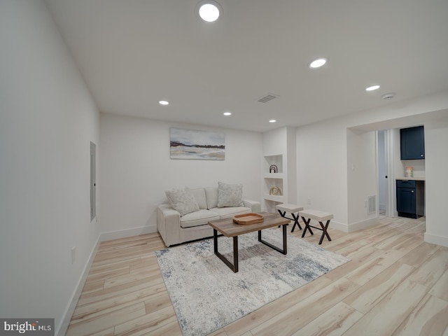 living room featuring electric panel and light hardwood / wood-style floors