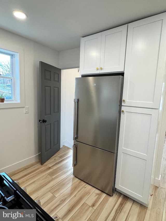 kitchen with white cabinetry, stainless steel fridge, and light hardwood / wood-style flooring