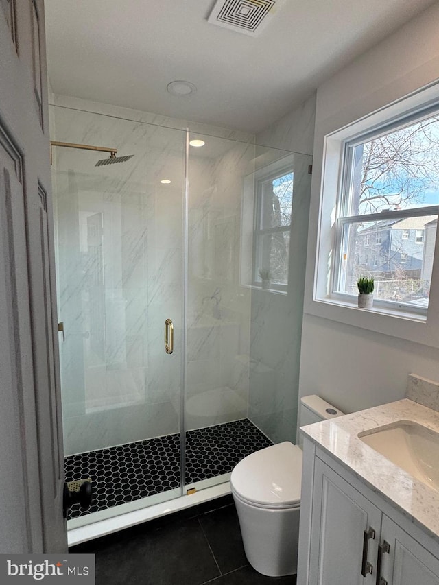 bathroom featuring tile patterned floors, vanity, toilet, and a shower with door