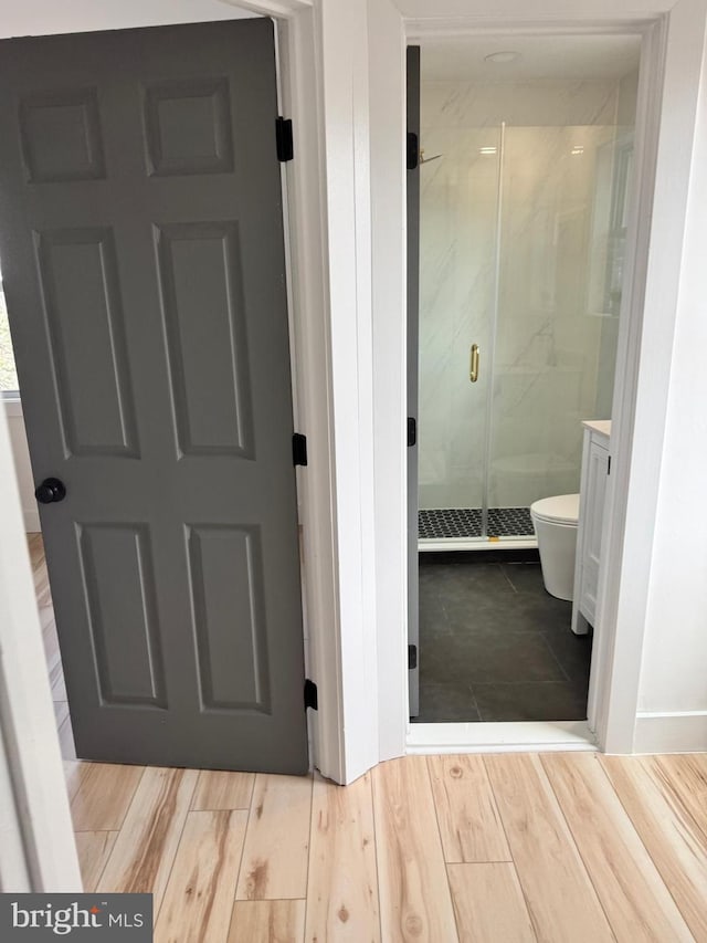 bathroom featuring hardwood / wood-style flooring, toilet, and an enclosed shower