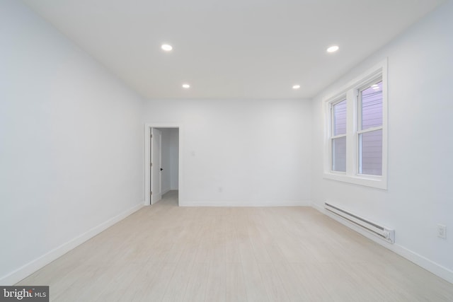 unfurnished room featuring baseboard heating and light hardwood / wood-style flooring