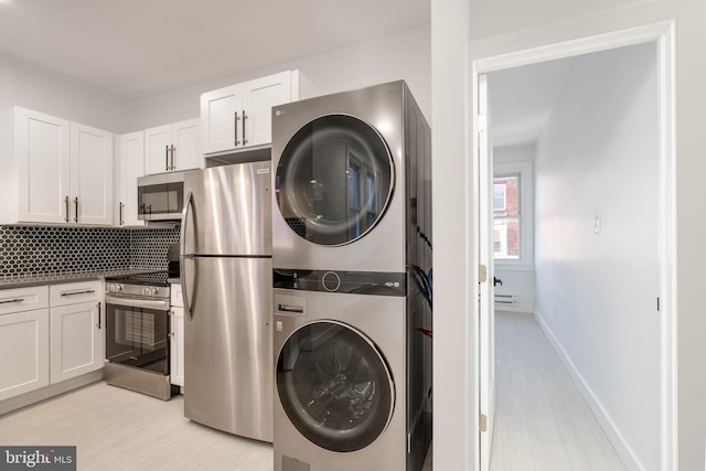 laundry area featuring stacked washer and clothes dryer and light wood-type flooring