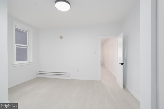 empty room with baseboard heating and light hardwood / wood-style floors