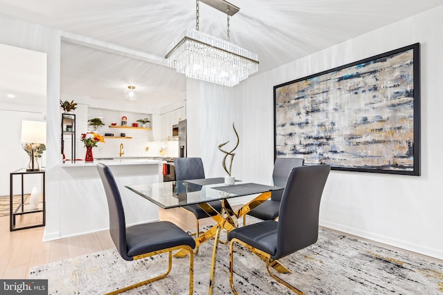 dining space with sink, a chandelier, and light wood-type flooring