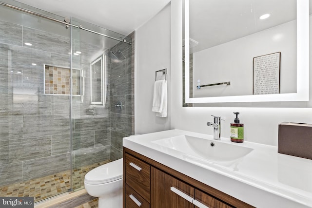 bathroom with vanity, a shower with shower door, and toilet