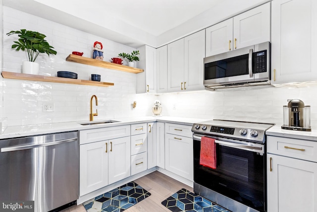 kitchen with appliances with stainless steel finishes, sink, and white cabinets