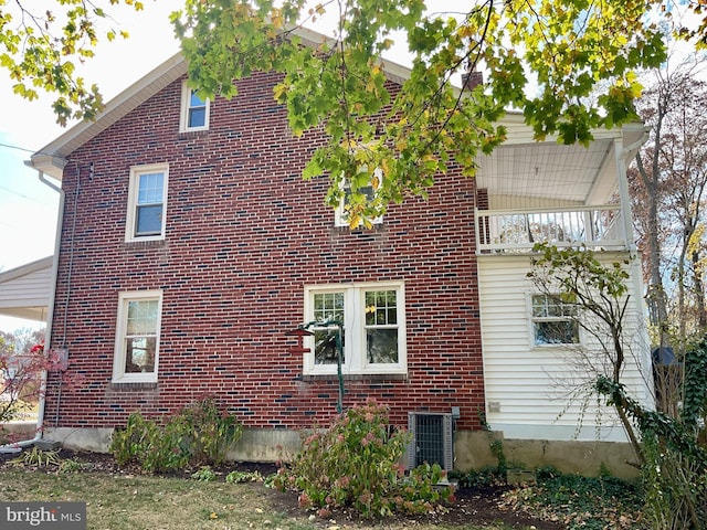 view of side of property with central AC unit and a balcony