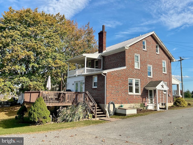 back of house featuring a wooden deck and a balcony