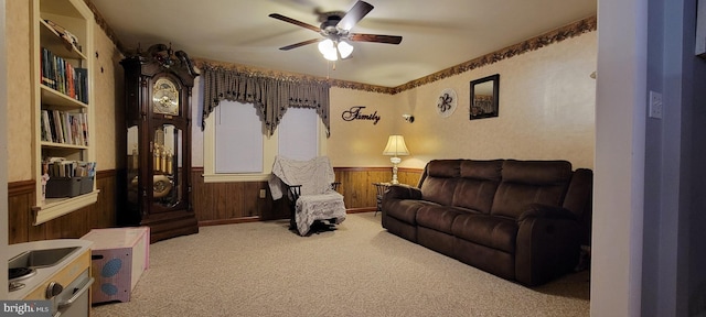 living room featuring light carpet, ceiling fan, and wood walls