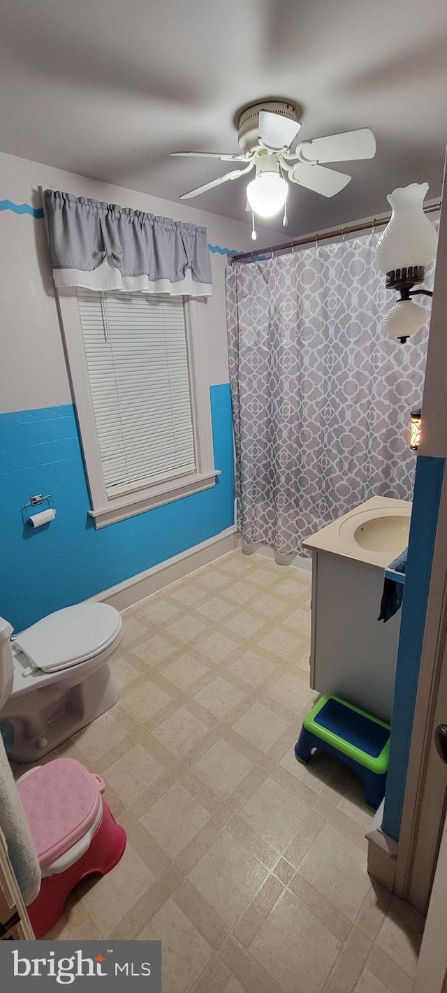 bathroom featuring a shower with curtain, ceiling fan, vanity, and toilet