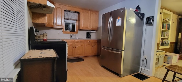 kitchen with stove, sink, stainless steel refrigerator, and light wood-type flooring