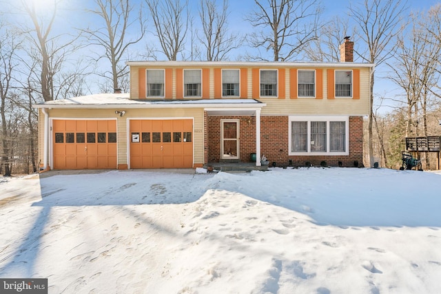 view of front of house featuring a garage, driveway, brick siding, and a chimney