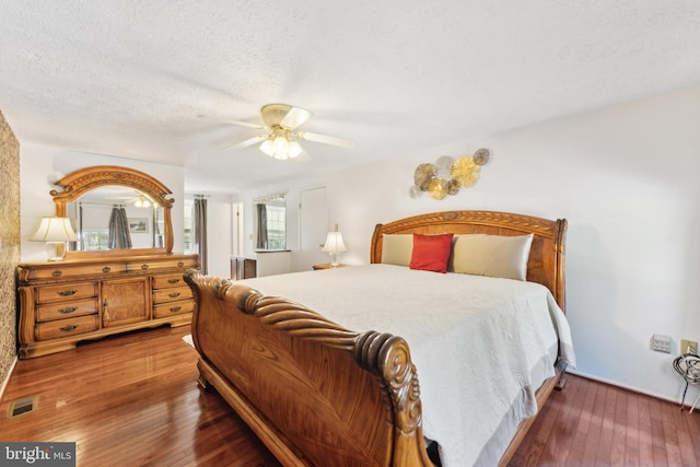 bedroom featuring ceiling fan, dark wood-type flooring, and a textured ceiling