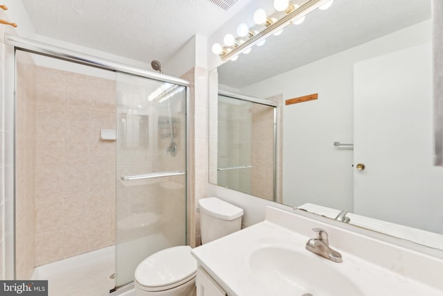 bathroom featuring a textured ceiling, toilet, walk in shower, and vanity