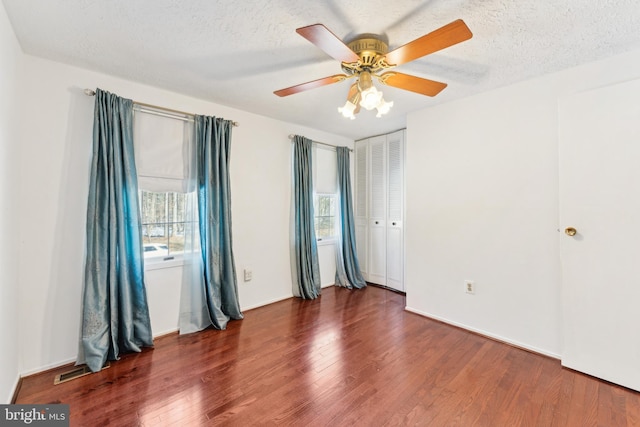 spare room with ceiling fan, a textured ceiling, and dark hardwood / wood-style flooring