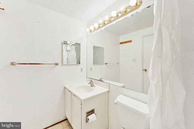 bathroom with toilet, a textured ceiling, tile patterned floors, and vanity