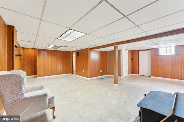 sitting room featuring a paneled ceiling and wooden walls