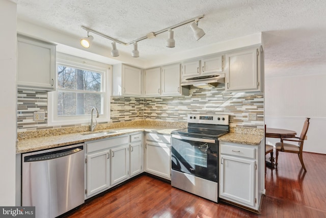 kitchen with white cabinets, appliances with stainless steel finishes, sink, dark hardwood / wood-style floors, and light stone counters