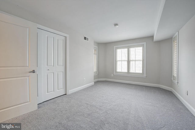 unfurnished bedroom featuring light colored carpet and a closet