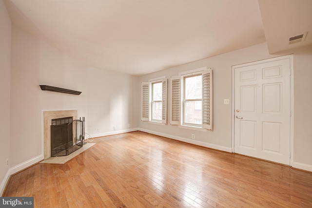 unfurnished living room featuring a premium fireplace and light hardwood / wood-style flooring