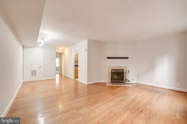 unfurnished living room featuring a high end fireplace and light hardwood / wood-style floors