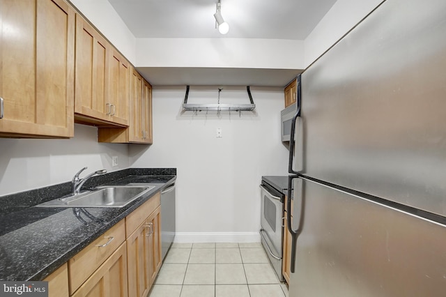 kitchen featuring stainless steel appliances, dark stone countertops, sink, and light tile patterned floors